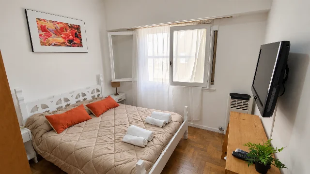 Dormitorio principal con cama grande, ventana y muebles de madera.